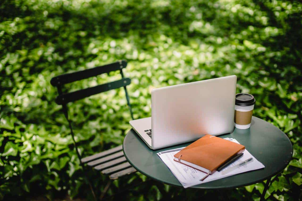 Cozy table with laptop and notebook in garden